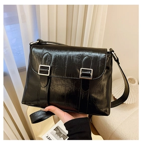 Gros plan d'un sac à bandoulière en cuir plissé noir avec boucles argentées vintage