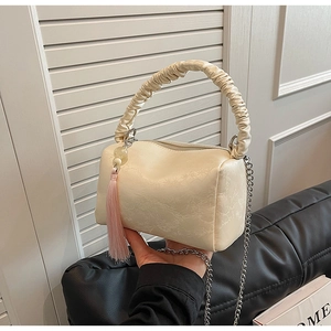 Detail view of cream white pleated pillow bag with floral texture and pink tassel charm