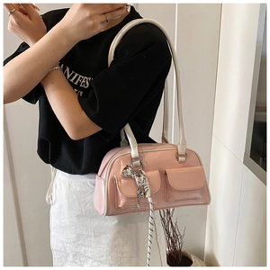 Detalle de bolso rosa brillante con bolsillos frontales dobles y colgante de lazo plateado