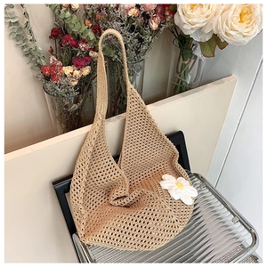 Detail of hand-woven crochet shoulder bag featuring a 3D white floral accent