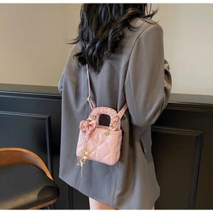Detail of pink patent leather quilted mini bag with silk bow and pearl charm accents
