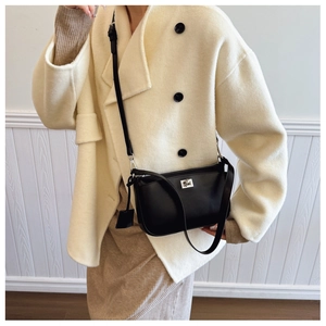 Detail of a matte black crossbody bag featuring a silver twist lock and adjustable strap