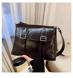 Détail du sac bandoulière en cuir verni marron foncé avec boucles argentées et rabat