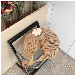 Detail of woven straw tote bag featuring a 3D handmade crochet sunflower on a chair
