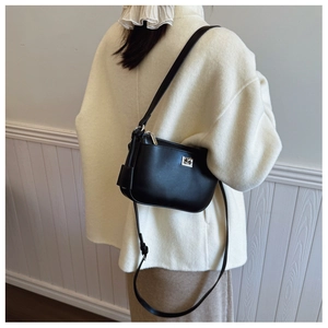 Rear view of black matte crossbody bag with silver buckle worn by a model