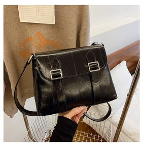 Détail du sac à bandoulière en cuir ciré brillant noir avec boucles vintage et plis