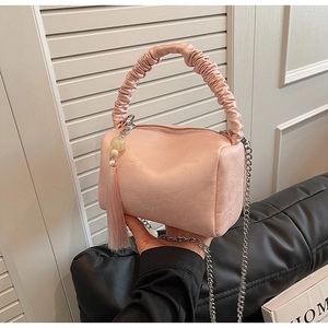 Detailed close-up of pink ruched pillow bag with silver chain strap and beaded tassel