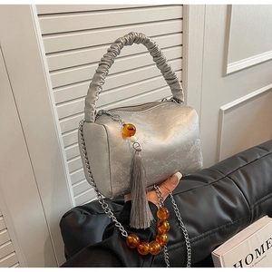 Detail of silver metallic crossbody bag with floral texture and pleated handle