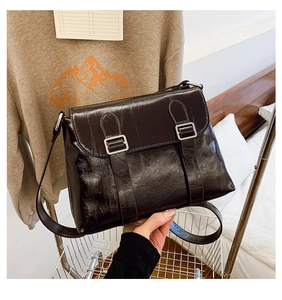 Détail du sac messager marron foncé brillant avec boucles argentées et rabat