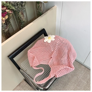 Detail showing pink crochet tote bag texture with 3D white flower on a folding chair