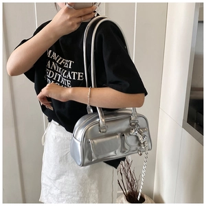 Detalle de bolso de hombro plateado metalizado con dos bolsillos y colgante de corazón