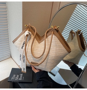 Detail of handwoven straw tote bag with brown leather trim and decorative brand ribbon