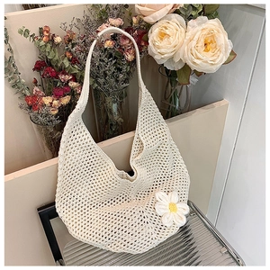 Detail of hollow woven shoulder bag with a 3D white daisy flower on cream crochet texture