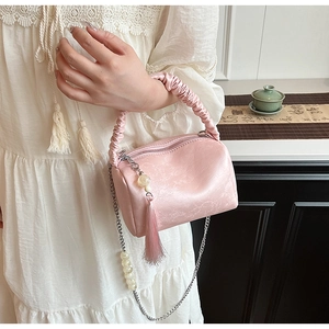 Detailed shot of a pink pleated bag with pearl chain strap and tassel charm detail