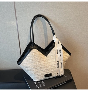 Detail of woven straw tote bag with black leather trim and decorative ribbon detail