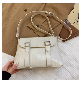 Détail du sac bandoulière en cuir crème avec boucles argentées et bandoulière réglable chic