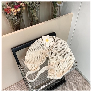 Detailed close-up of beige woven hollow shoulder bag with 3D white crochet flower daisy