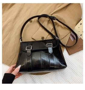 Détail de la texture cuir ciré noir brillant et boucle argentée du sac à bandoulière