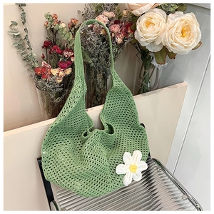 Detail of light green hollow crochet shoulder bag with a white 3D daisy flower charm