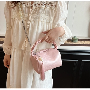 Detail of pink pleated pillow bag with elegant pearl chain strap and tassel charm