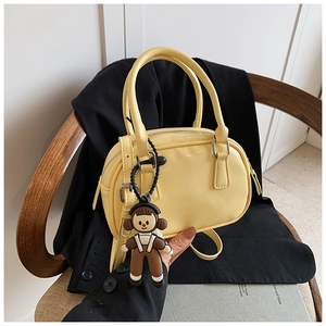 Detail of pale yellow glossy mini bowling bag on a chair with a detachable strap