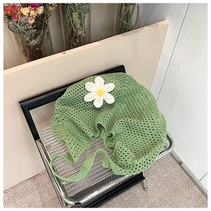 Detail of green crochet tote bag with white daisy applique on a silver chair