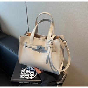 Detail of off-white handbag featuring silver metal twist lock and decorative straps
