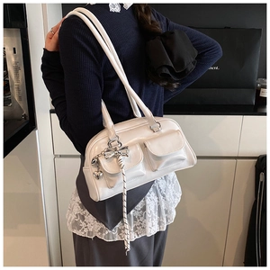 Detalle del bolso Boston blanco brillante con bolsillos frontales y colgantes de corazón