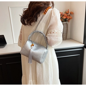 Detail of silver pleated pillow bag featuring amber bead chain and long fringe tassel