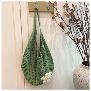 Detail of green knit tote bag featuring a 3D white flower and woven mesh texture