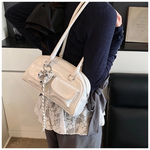 Detalle del bolso Boston de charol blanco con bolsillos frontales y colgante de lazo