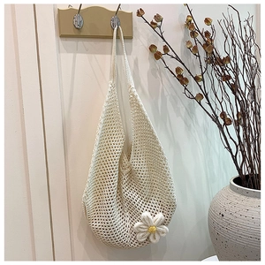 Detailed close-up of ivory woven tote bag featuring a delicate handmade knit daisy flower