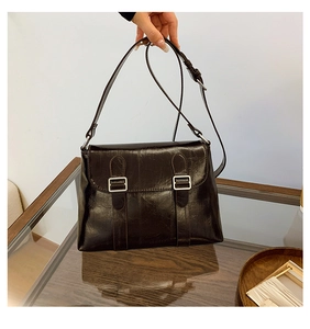 Détail d'un sac à bandoulière vintage marron foncé avec boucles et texture cuir ciré