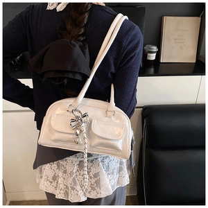 Detalle del bolso bowling blanco brillante con bolsillos dobles y colgante de lazo plateado