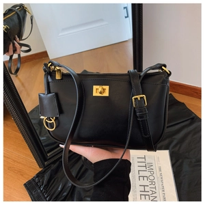 Detail of black leather crossbody bag with golden twist lock and mirror reflection view