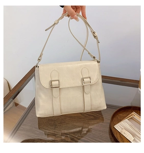 Détail du sac bandoulière crème avec sangles à boucles métalliques et texture rétro