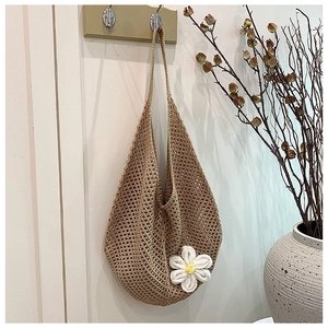 Detail of hand-woven hollow knit tote bag featuring a white 3D daisy flower accent