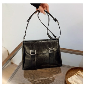 Détail de la surface en cuir verni brillant et de la boucle argentée sur le sac noir