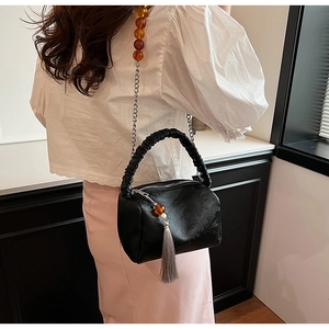 Detail of black pleated bag featuring beaded silver chain and elegant fringe tassel