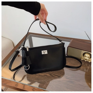 Close-up of black leather crossbody bag with silver twist lock and adjustable strap