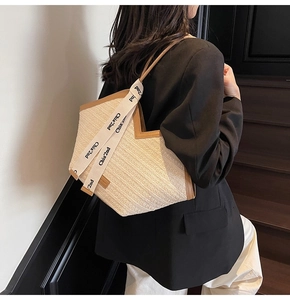 Detail of woven beach tote with brown leather handles and a decorative branded ribbon