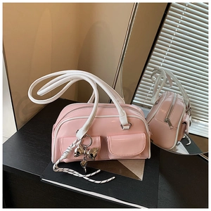 Detalle de bolso rosa de charol con amuleto de lazo y dos bolsillos exteriores con solapa