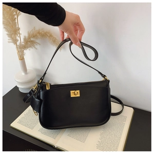 Close-up of black crossbody bag with golden twist-lock closure and leather texture