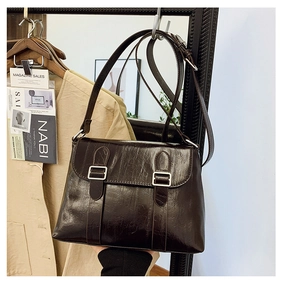 Détail du sac bandoulière en cuir brillant marron avec boucles argentées décoratives