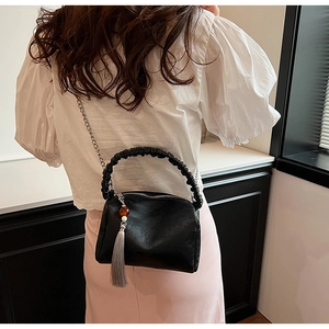 Detail of ruched handle and silver chain on a black faux leather pleated pillow bag