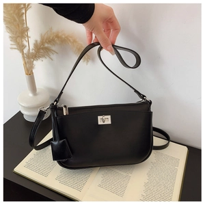 Detail of black crossbody bag with silver twist-lock closure and leather tag charm