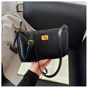 Detail of black leather crossbody bag featuring gold twist-lock and adjustable strap