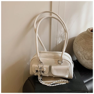 Detalle del bolso Boston blanco con bolsillos dobles y colgante de lazo plateado