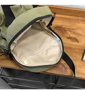 Detailed interior of green nylon backpack showing cream lining and internal zipper pocket