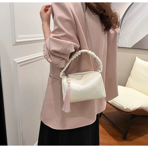 Detail of cream pleated shoulder bag with silver chain and marble texture on leather